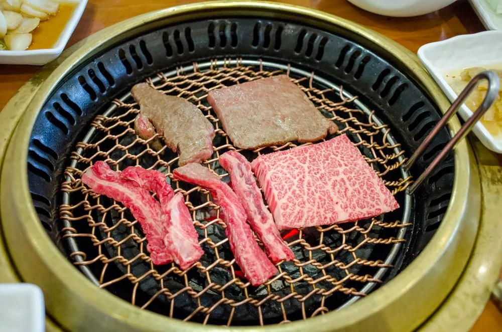 Marbled beef grilling on a traditional Korean barbecue